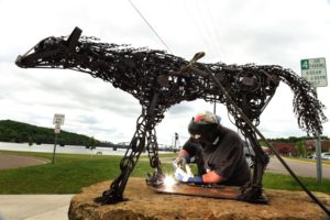 Welder and artist John Hughes installs "Trap", an original outdoor sculpture of a life-sized female wolf made out of animal traps by Dale Lewis, in downtown Stillwater, Wednesday, June 1, 2016. (Pioneer Press: Scott Takushi)